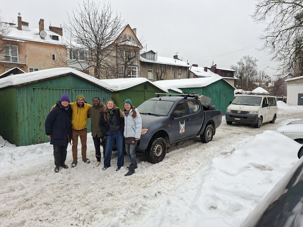 Bénévoles avec un pick-up et une camionnette dans une cour enneigée